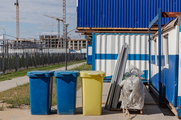 Contenitori per la raccolta differenziata dei rifiuti in cantiere. Cestini per la raccolta differenziata in prossimità della recinzione in ferro e delle capanne di costruzione. contenitore della spazzatura.