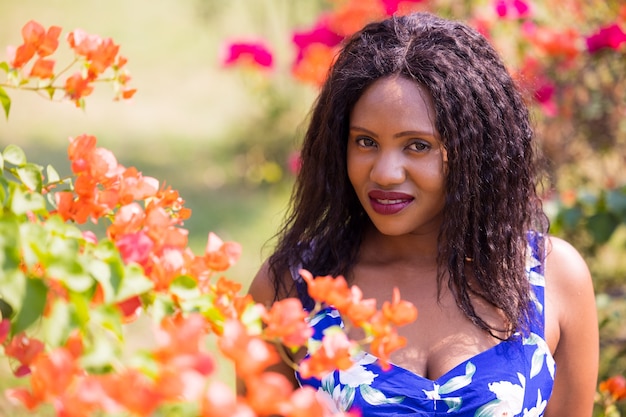 Contenta donna nera fiori profumati nel parco.