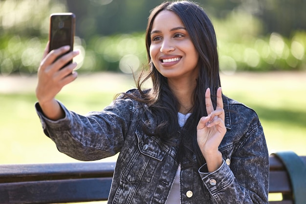 Contenuti e confortevoli Scatto di una bellissima giovane studentessa che usa il telefono mentre è seduta fuori