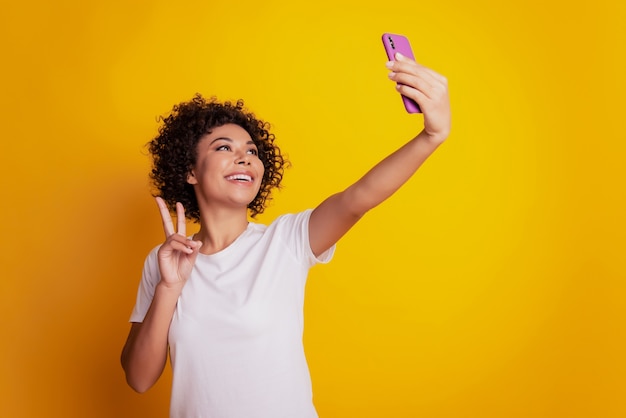 Contenuto alla moda allegro carino carino adorabile ragazza tenere il telefono sparare selfie spettacolo v-sign