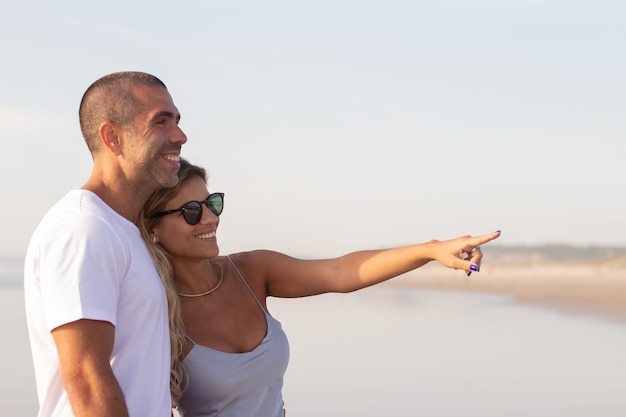 Contenuto coppia maschile e femminile che trascorrono del tempo in spiaggia. Marito e moglie in abiti casual che camminano, parlano, indicano. Vacanza, felicità, concetto di relazione