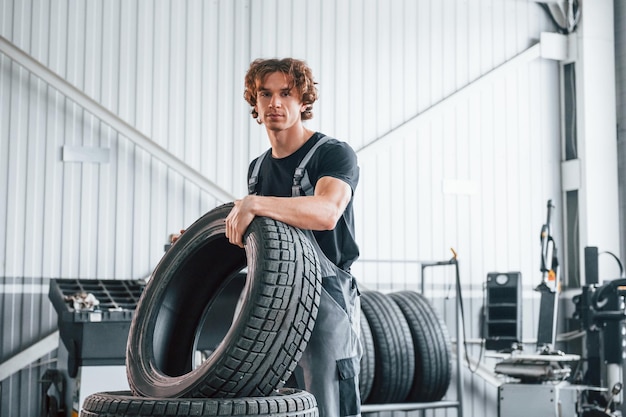 Contiene pneumatici L'uomo adulto in uniforme di colore grigio lavora nel salone dell'automobile