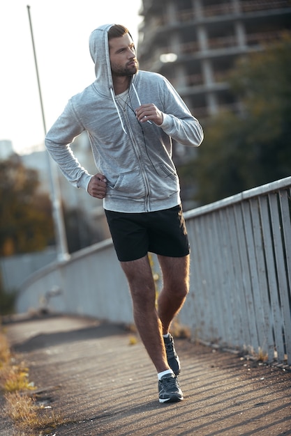 Continua a correre! Per tutta la lunghezza del bel giovane che guarda lontano mentre corre lungo la strada