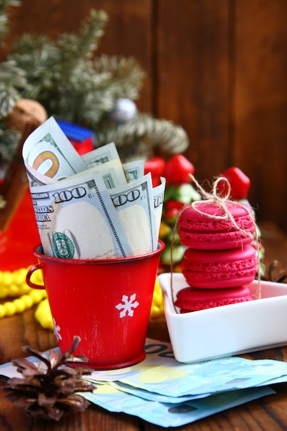 Contorto banconote da un dollaro in un secchio di Natale rosso, euro e amaretti rosa