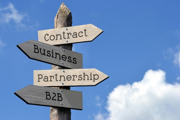 Contratto B2B business partnership cartello in legno con quattro frecce cielo con nuvole