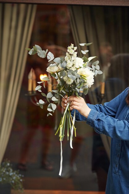 Contro la finestra vista ravvicinata della donna che è con i fiori in mano