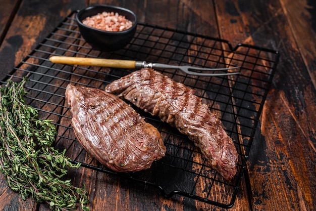 Controfiletto alla griglia o bistecca di carne di manzo Bavette su un griil con erbe aromatiche Sfondo in legno Vista dall'alto