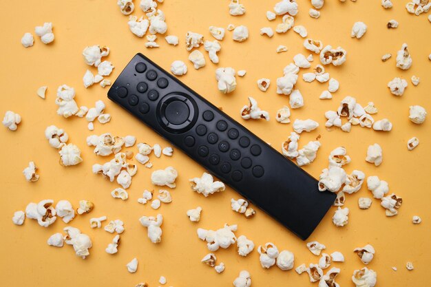 Controllo a distanza con popcorn diffusi su sfondo giallo Film e concetto di cinema