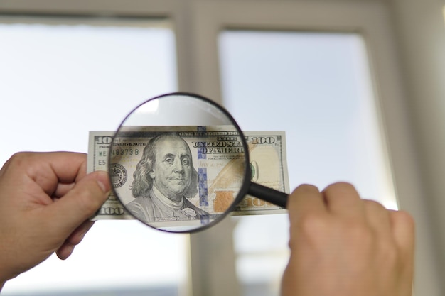 Controllo della luce di denaro contraffatto 100 dollari contro la finestra in mano Controllare la filigrana sulla nuova trasparenza della banconota da cento dollari della valuta americana