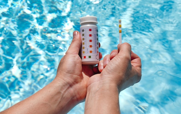 Controllo della qualità dell'acqua di una piscina con l'aiuto di una striscia reattiva con valore di ph cloro e alghicida