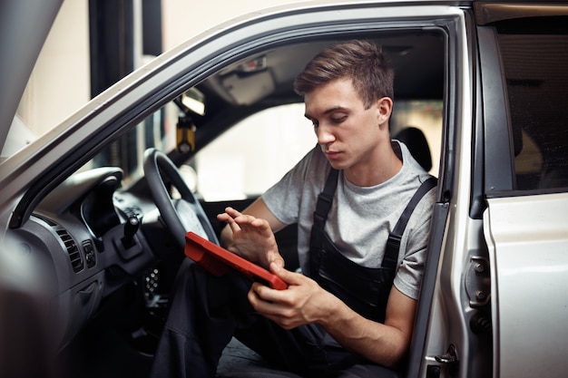 Controllo di un'auto all'autoservice: un giovane meccanico è alla ricerca di insetti.