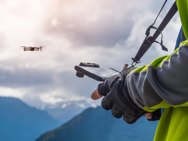 Controllo di un drone in alta montagna Un uomo tiene un pannello di controllo del drone il drone si blocca in aria primo piano delle mani