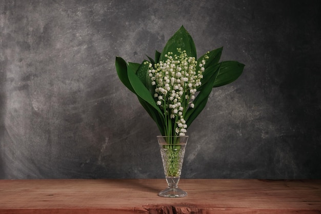 Convallaria majalis su un tavolo di legno rosso bellissimo sfondo grigio della parete