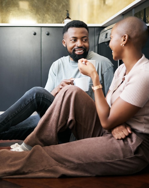 Conversazione coppia felice e africana con caffè per la pace amore e cura sul pavimento della cucina Comunicazione sorriso e uomo e donna neri che bevono tè mentre parlano della loro relazione