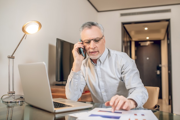 Conversazione d'affari. Uomo maturo che parla al telefono e sembra coinvolto