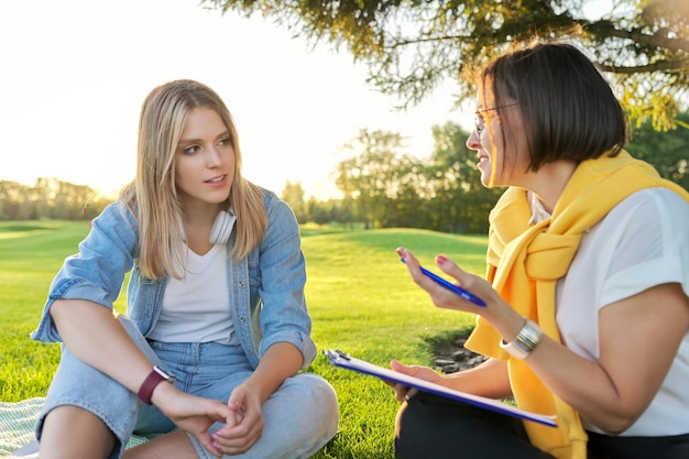 Conversazione di giovane donna con psicologo assistente sociale all'aperto durante la riunione nel parco sul prato