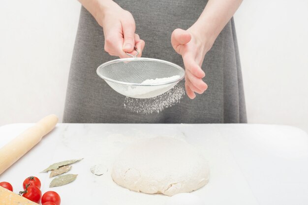 Cook fa l'impasto della pizza, cospargendolo di farina