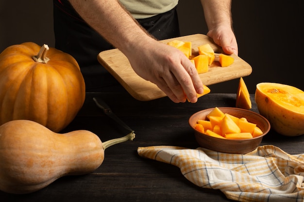 Cook getta fette di zucca da un tagliere in una ciotola profonda.