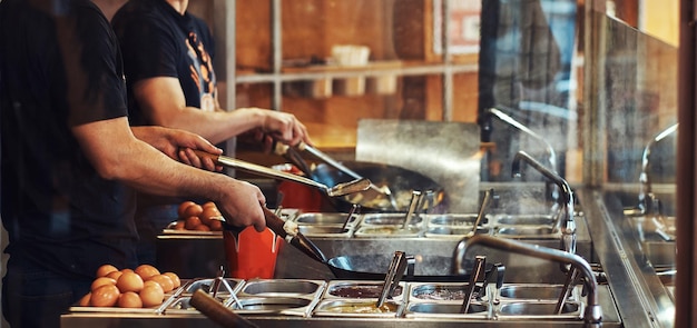 Cook sta mescolando le verdure in un wok. Processo di cottura in un ristorante asiatico.