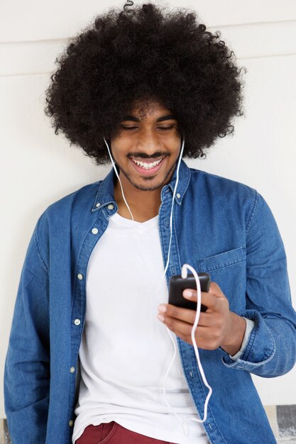 Cool ragazzo sorridente con il cellulare e gli auricolari