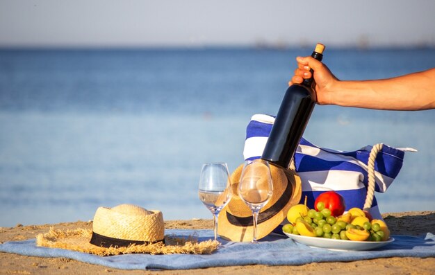 Coperta da picnic, vino, frutta, bellissima spiaggia di mare. Messa a fuoco selettiva