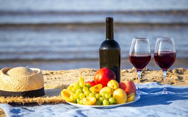 Coperta da picnic, vino, frutta, bellissima spiaggia di mare. Messa a fuoco selettiva