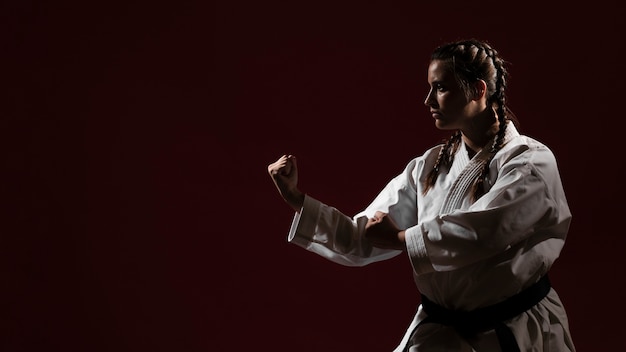 Copi lo spazio il fondo e la donna rossi in uniforme bianca di karatè