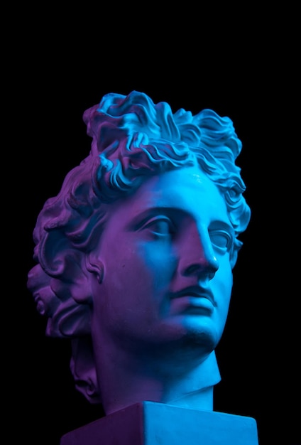 Copia in gesso bianco dell'antica statua di Apollo Dio del sole testa per artisti isolati su sfondo nero. Scultura in gesso del volto dell'uomo. Tonalità blu e viola.