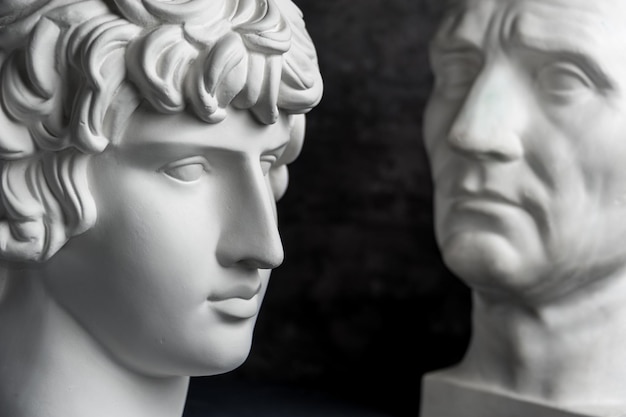 Copia in gesso bianco dell'antica statua di Guy Julius Caesar Octavian Augustus e Antinous testa per artisti su uno sfondo scuro con texture. Scultura in gesso del volto dell'uomo.