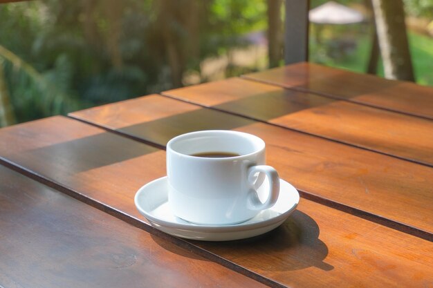 Coppa bianca di caffè su un tavolo di legno sullo sfondo della natura in un hotel tropicale