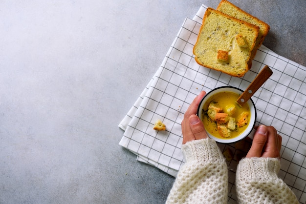 Coppa con zuppa di crema di carote in mani di ragazza