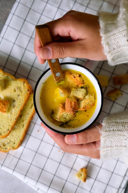 Coppa con zuppa di crema di carote in mani di ragazza