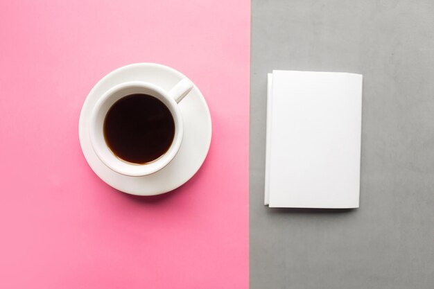 Coppa da caffè e modello bianco in bianco su carta geometrica grigia e rosa con consistenza di sfondo