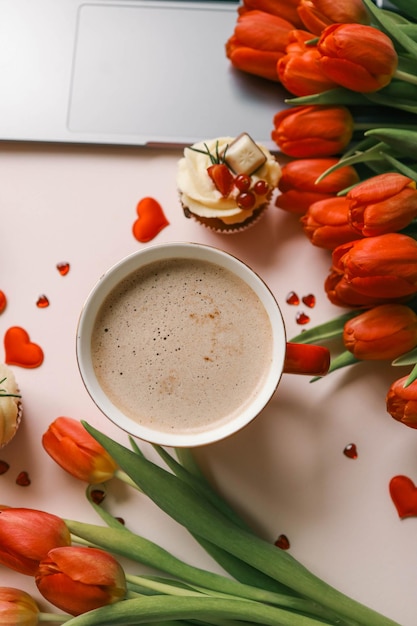 Coppa di caffè bouquet di tulipani rossi e portatile vista superiore piatto posa sfondo festivo