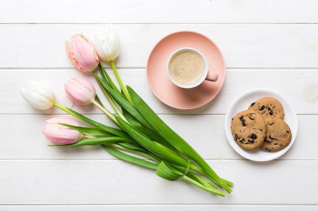 Coppa di caffè con biscotti di caffè e tulipani su uno sfondo colorato Cartella di auguri primaverile vista superiore