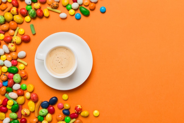 Coppa di caffè con cioccolatini e caramelle colorate Vista superiore sullo sfondo del tavolo con spazio di copia