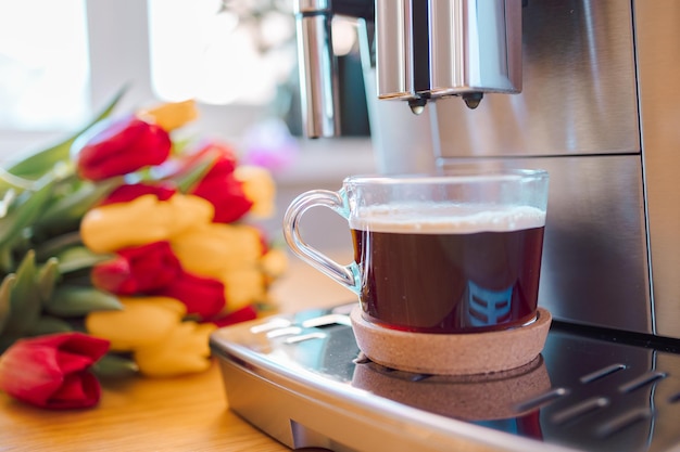 Coppa di caffè con latte e fiori di tulipano sul tavolo di cucina in legno cappuccino appena preparato