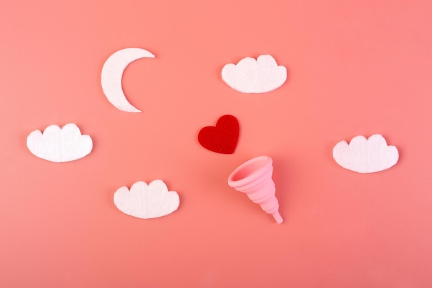 Coppa mestruale rosa in silicone con luna e nuvole flatlay su sfondo rosa Salute delle donne