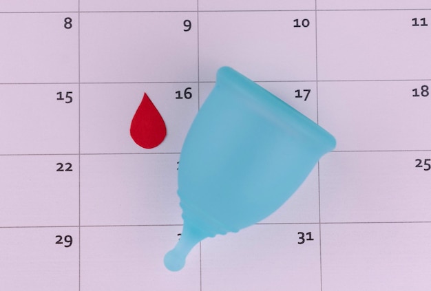 Coppa mestruale sullo sfondo del calendarioIl concetto di mestruazioni