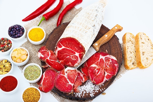 Coppa stagionata affettata con spezie e pezzi di ciabatta italiana. Isolato su bianco.