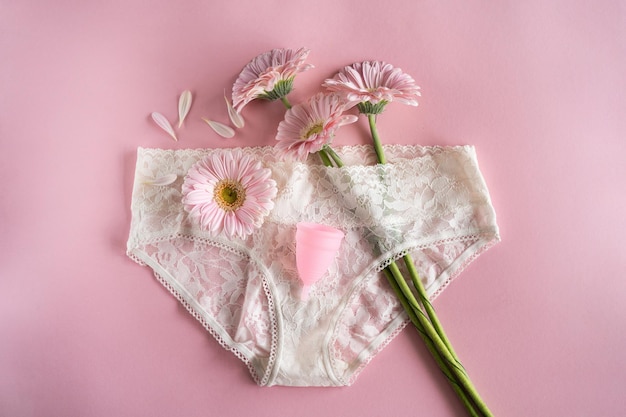 Coppetta mestruale in silicone Salute delle donne e igiene alternativa Coppa con fiore su sfondo rosa Alternative zero rifiuti
