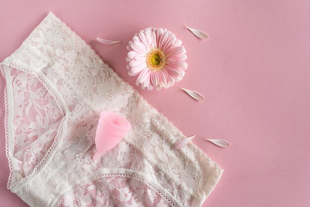 Coppetta mestruale in silicone Salute delle donne e igiene alternativa Coppa con fiore su sfondo rosa Alternative zero rifiuti