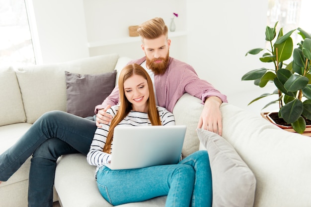 Coppia a casa sul divano con laptop