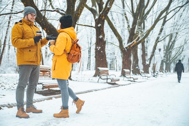 Coppia a piedi dal parco cittadino innevato a parlare di socializzazione. appuntamento romantico in inverno. Natale sta arrivando