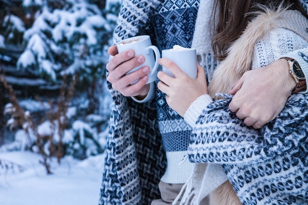 Coppia abbraccia e tiene tazze di caffè con marshmallow