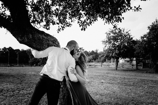 Coppia ad un appuntamento. Vestito viola. Sposa e sposo. Cammina nel campo. Storia d'amore. Foto in bianco e nero.