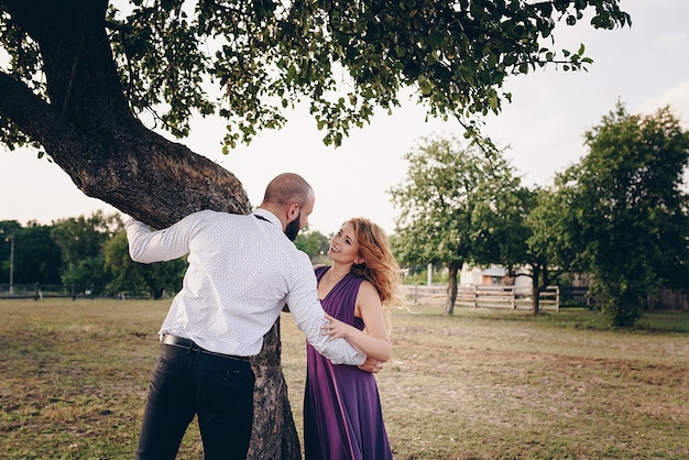 Coppia ad un appuntamento. Vestito viola. Sposa e sposo. Cammina nel campo. Storia d'amore.