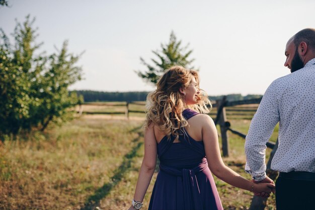 Coppia ad un appuntamento. Vestito viola. Sposa e sposo. Cammina nel campo. Storia d'amore.