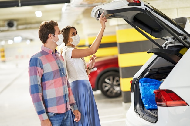 coppia adulta che indossa maschere nel parcheggio sotterraneo