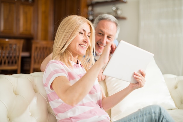 Coppia adulta utilizzando una tavoletta nella loro casa